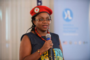 2017 Fellow Flavia Kalule Nabagabe speaks at the Next Steps Session of the 2019 Mandela Washington Fellowship Summit. The subject is wearing a red beret and matching necklace.