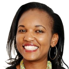 Headshot of a smiling woman wearing hoop earrings and a necklace