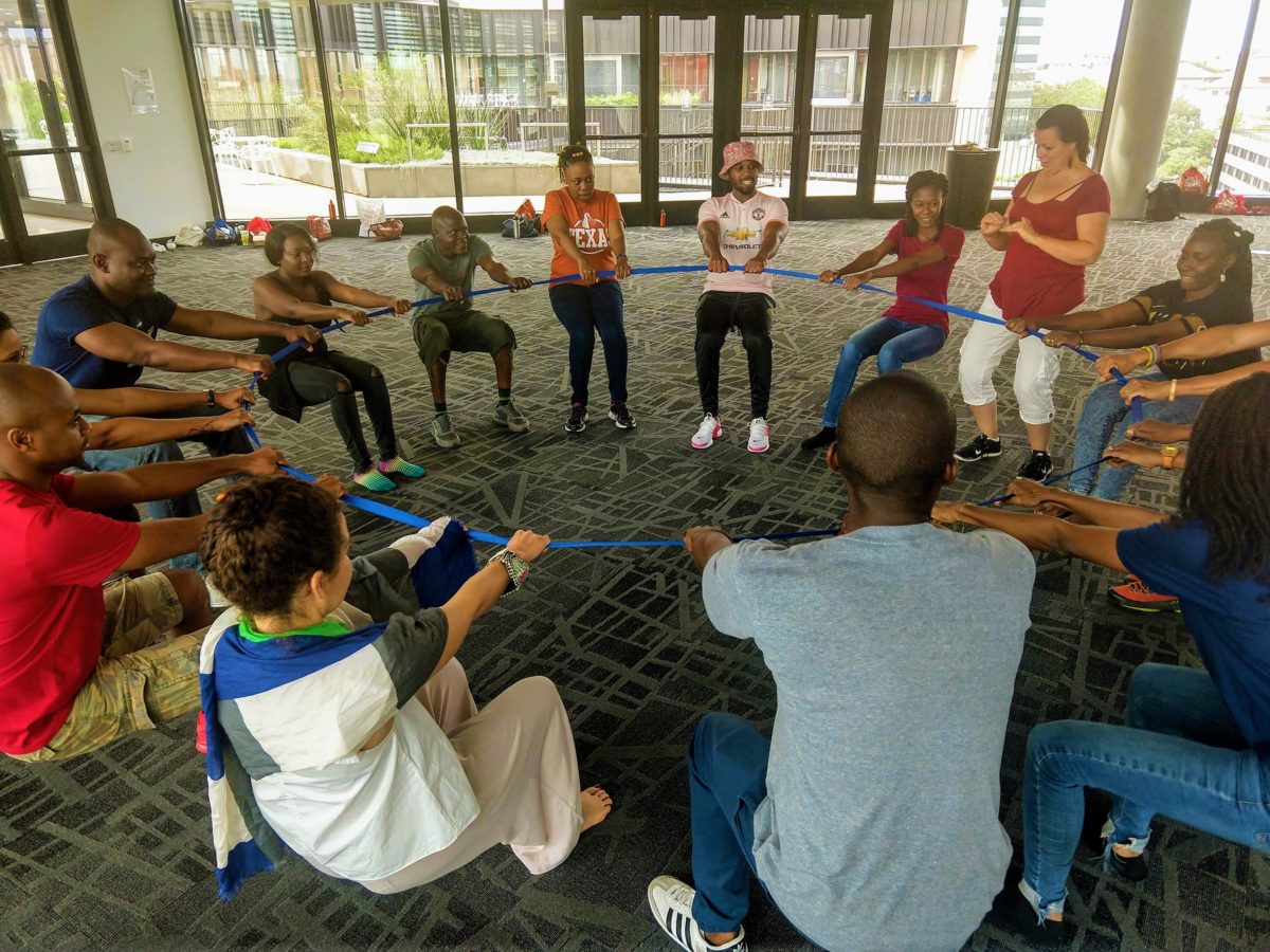 A group of Fellows at The University of Texas at Austin Leadership Institute participates in a Common Leadership Curriculum exercise, in which participants all pull on a rope while standing in a circle, guided by a facilitator.