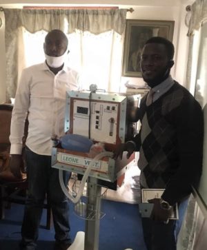 Two men stand on either side of a ventilator