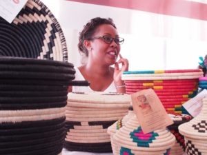 A woman in glasses stands behind a table covered in baskets