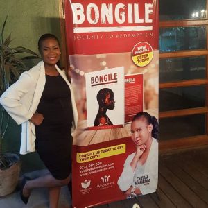 Chiedza stands next to a pop up banner advertising her book.