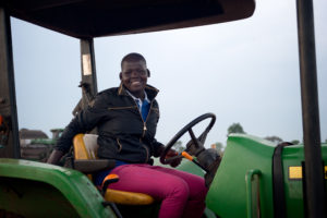 A man smiles as he sits in a piece of farm machinery