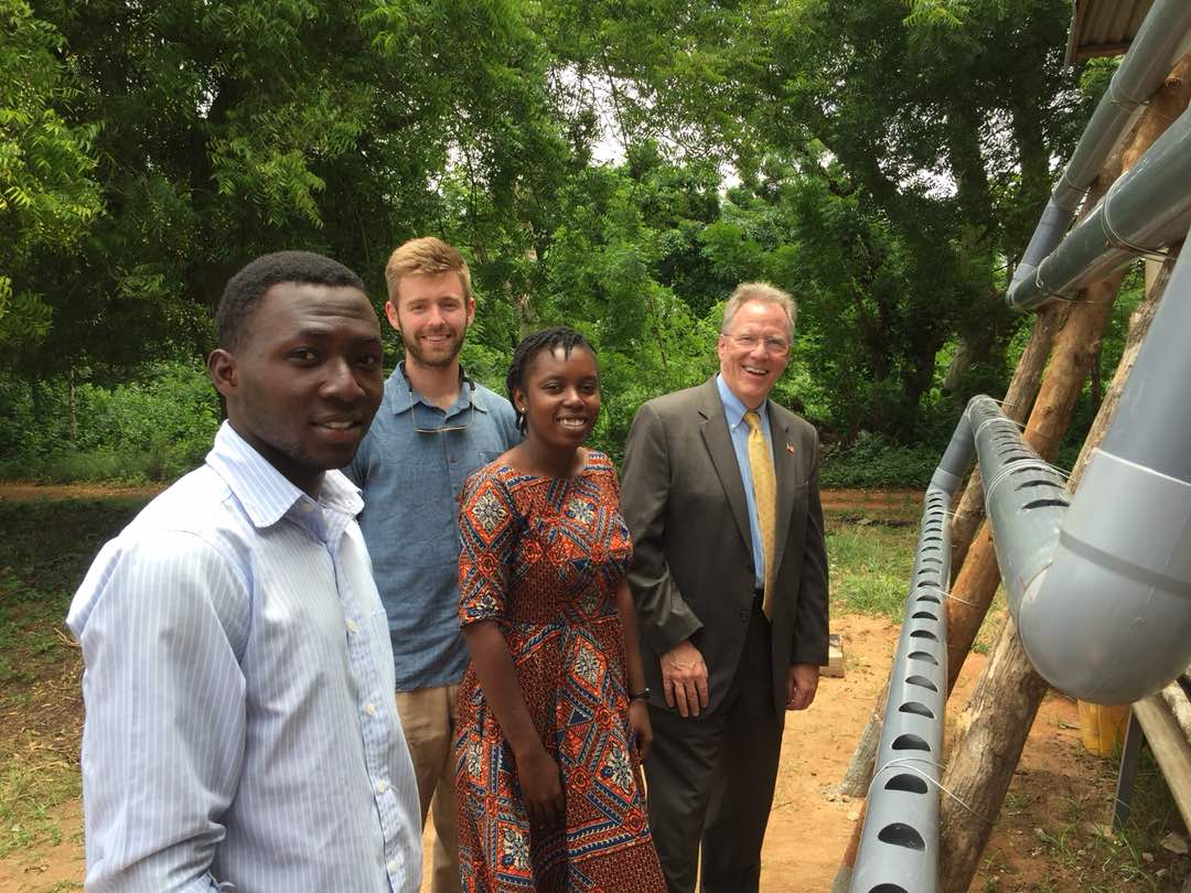 Reciprocal Exchange Participant Scott Massey stands next to a hydroponic farm with U.S. Ambassador to Togo David Gilmour, 2017 Fellow Alumna Delia Carmen Diabangouya, and student Marc Ptcholo.
