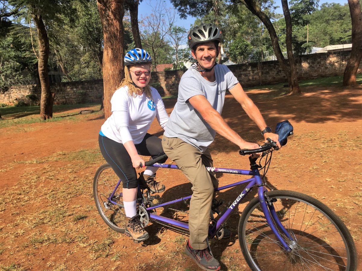 Reciprocal Exchange Participant Greg Milano sits on tandem bicycle with 2015 Fellow Alumna Jane Waithera Wairium