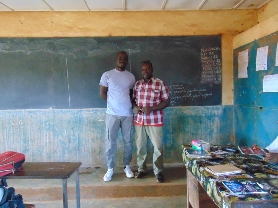 Two men stand in front of the blackboard in a classroom
