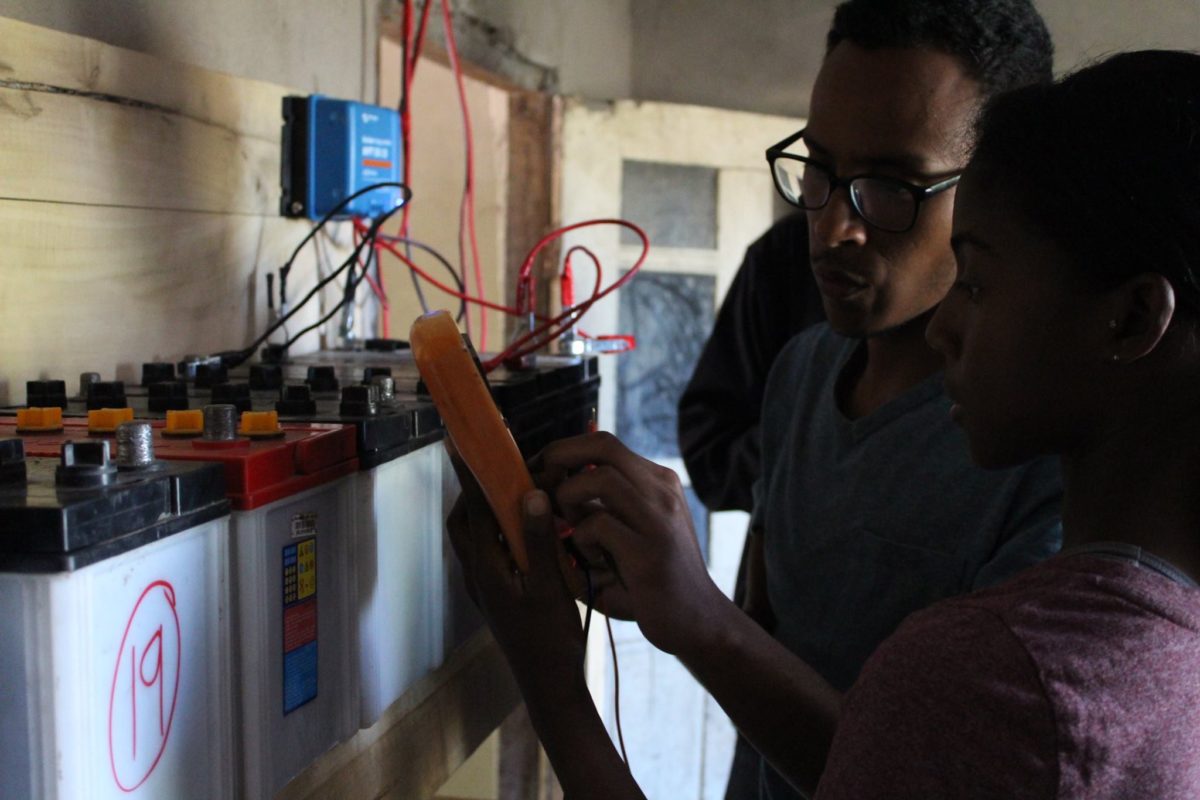 Reciprocal Exchange Participant Ryan Taylor and a woman connect wires to equipment and batteries