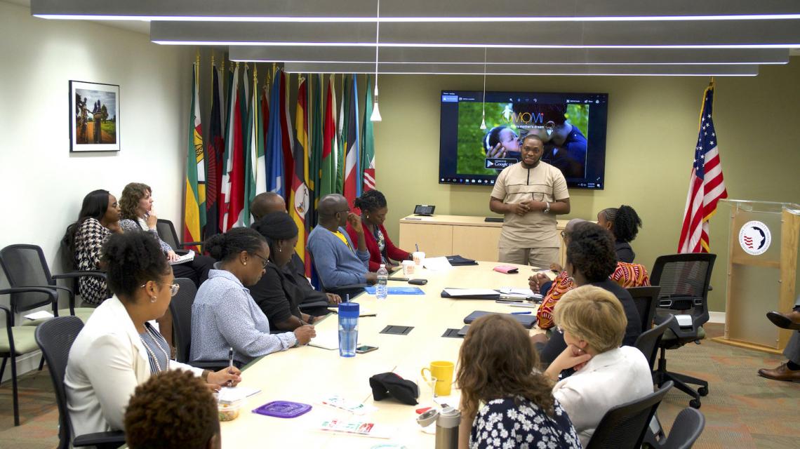 Charles presents to a group of individuals in a conference room.