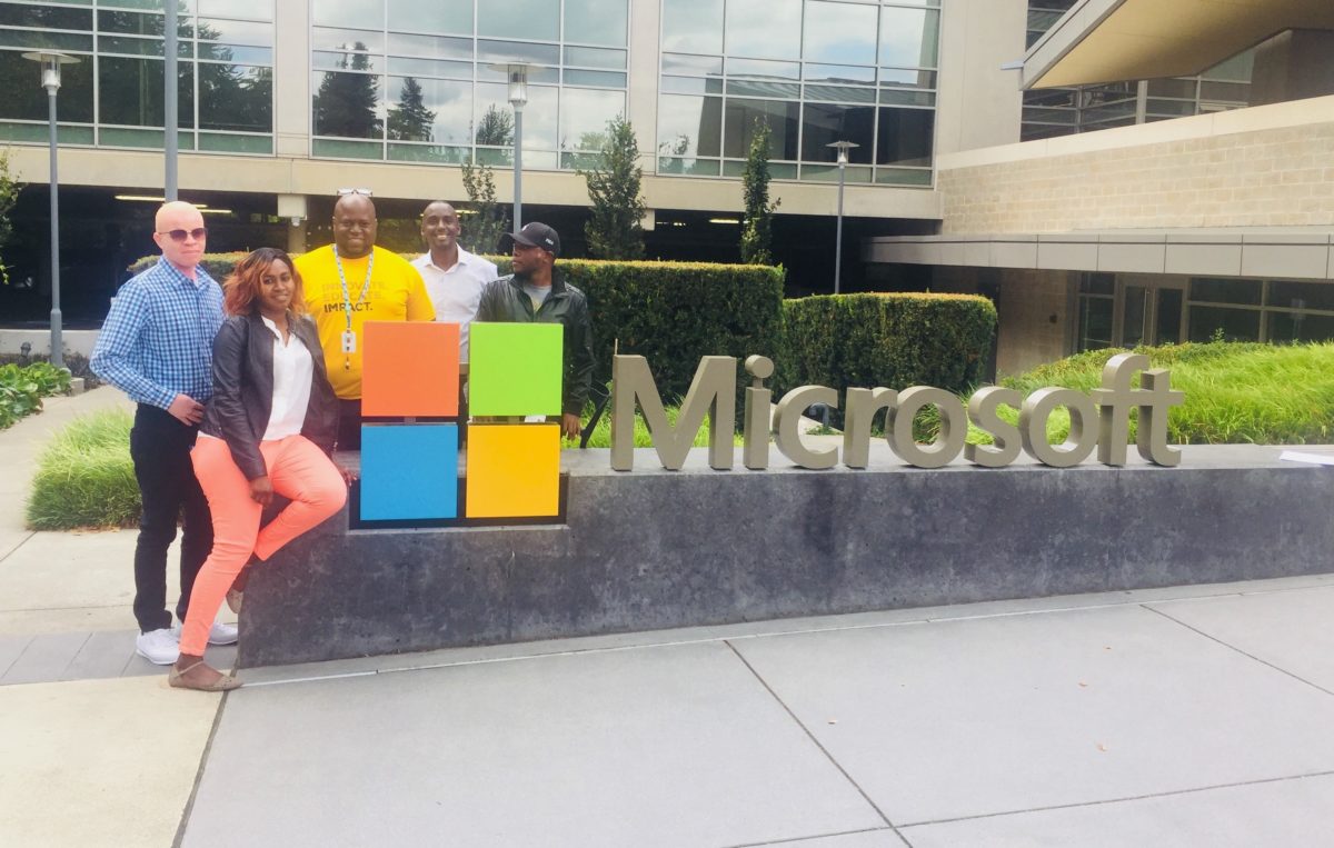 Fellows pose by a Microsoft sign outside an office building