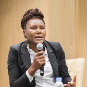 Candid photo of a woman in a black suit talking into a microphone