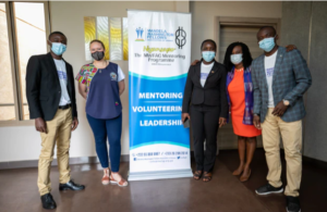 A group of people pose for a photo around a pop-up banner.