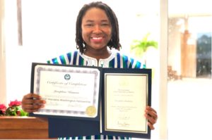 Woman smiles and holds up 2 certificates