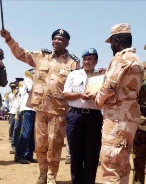 A woman hands 2 men in uniform a certificate