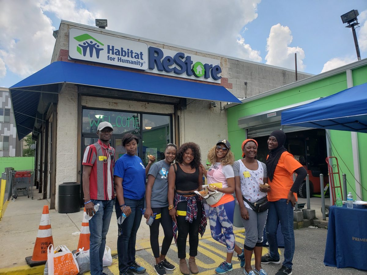 A group of Fellows stands in front of a Habitat for Humanity ReStore building