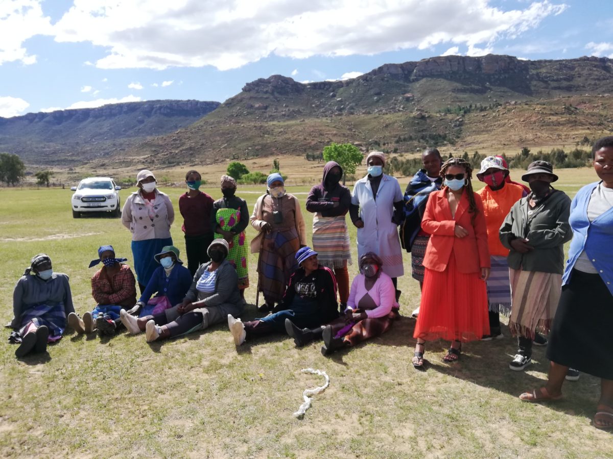 Group of women in an open field with a mountain behind them. 