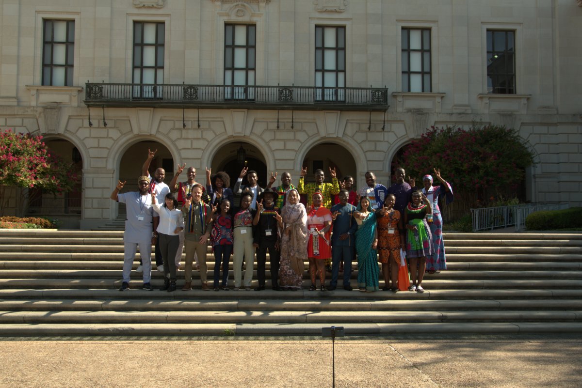 A group of young adults wearing cultural dress pose on steps.