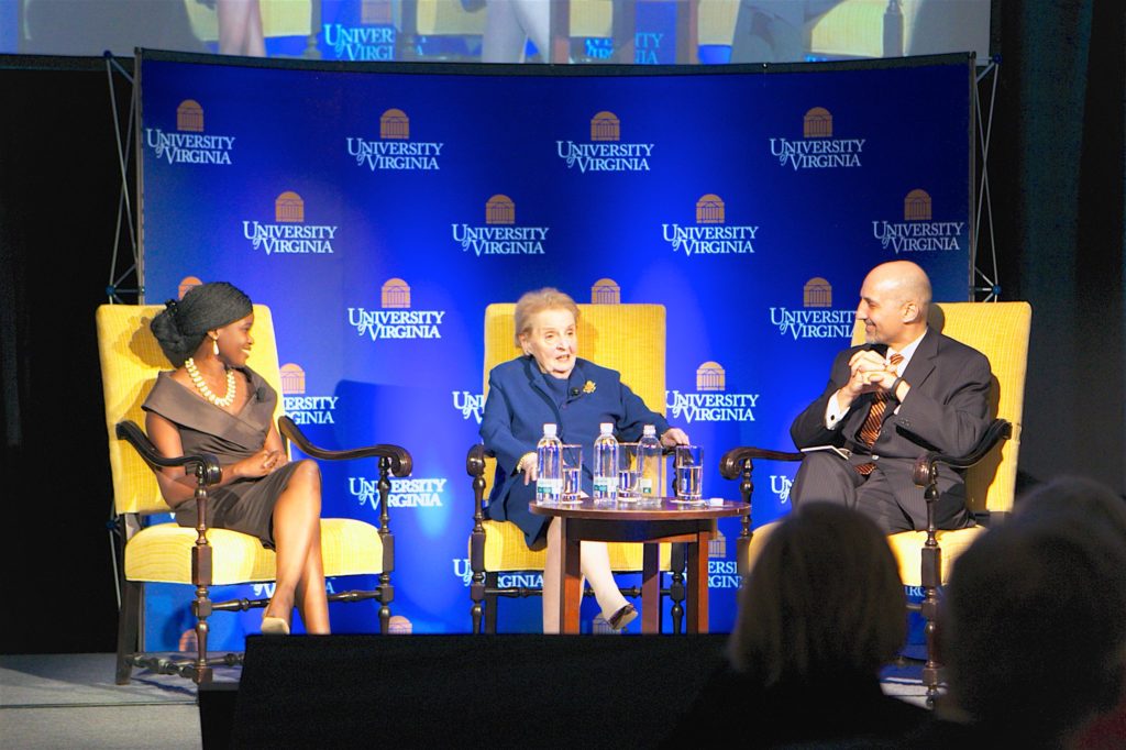 Three people sit in chairs on a stage