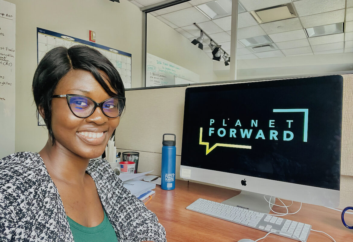 A young woman in glasses smiles for a selfie at her desk