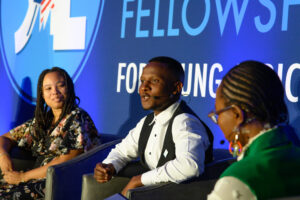 Candid photo of a panel discussion; man in business formal dress in center speaks