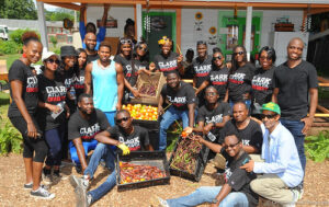 Group of people in matching black shirts that say Clark Atlanta University stand around boxes of produce, smiling for the camera