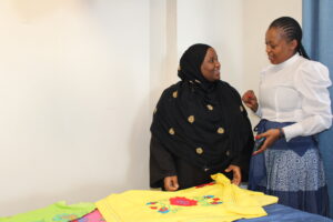 Women converse next to a table with yellow fabric on it